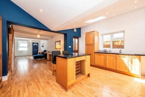 A modern kitchen with wooden cabinets, a black countertop, and a view of the outside through a window. - Charming Cottage 15 minutes to central London - Pass the Keys (Surbiton)