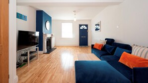 Ein Wohnzimmer mit Kamin, Fernseher, einer Couch und einer Tür.