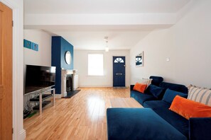Ein Wohnzimmer mit Kamin, Fernseher, einer Couch und einer Tür.