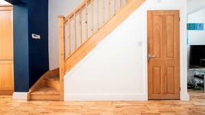 Eine Treppe mit Holzgeländern führt zu einer Zwischenebene, einer weißen Tür mit Holzvertäfelung und einer blauen Wand.