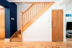 Eine Treppe mit Holzgeländern führt zu einer Zwischenebene, einer weißen Tür mit Holzvertäfelung und einer blauen Wand.