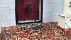 A red door with a decorative wreath, a black metal gate, and a tiled entrance area. - Cozy Retreat w/Coffee Bar & Private Entry (Houston)