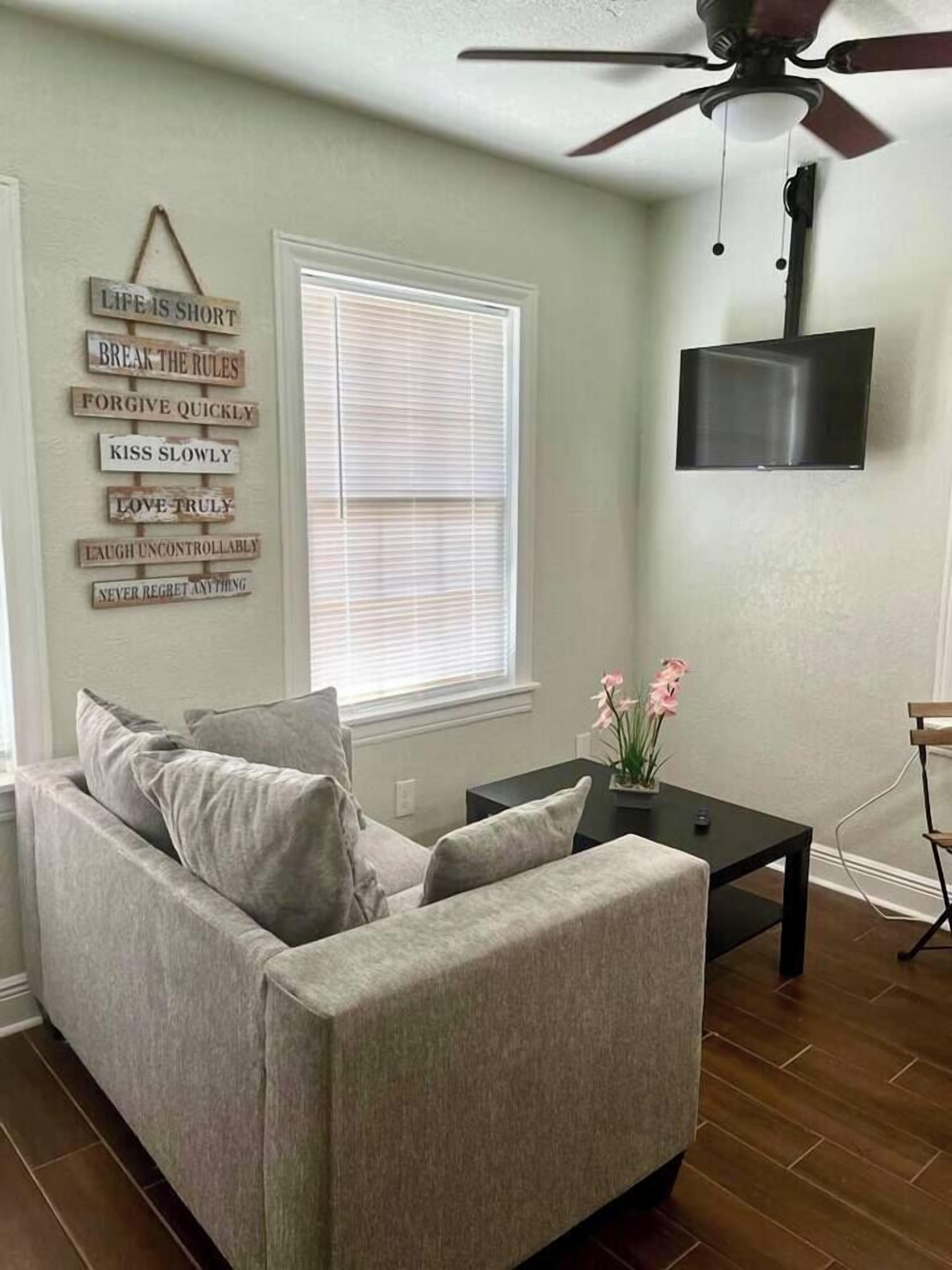 A living room with a grey sofa, a black coffee table, and a wall-mounted TV.