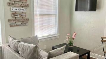 A living room with a grey sofa, a black coffee table, and a wall-mounted TV.