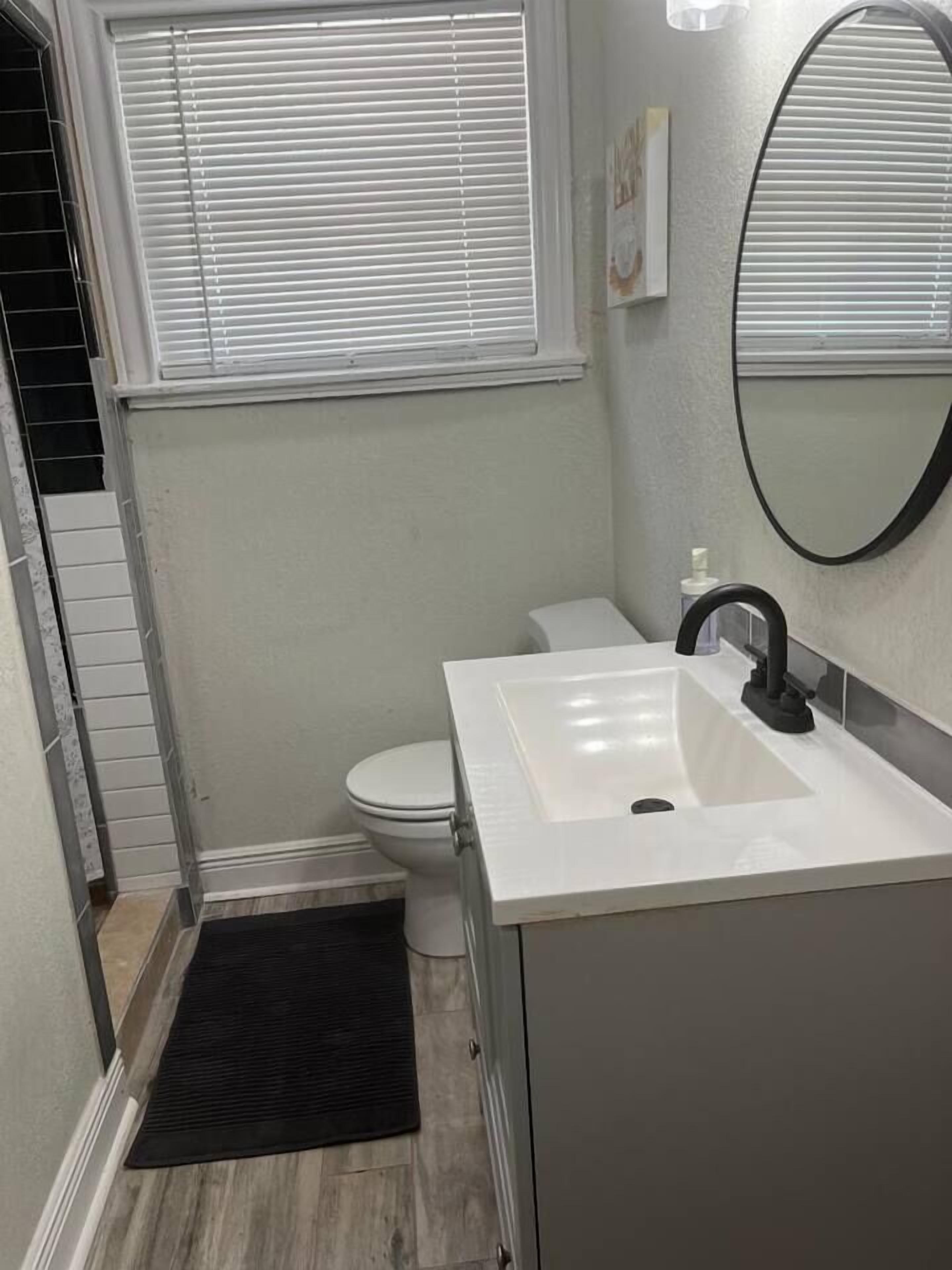 Une salle de bain avec un lavabo blanc, un robinet noir et des toilettes.