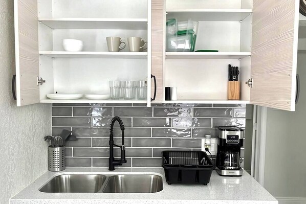 Een keuken met twee spoelbakken, een koffiezetapparaat en een afwasschaal.