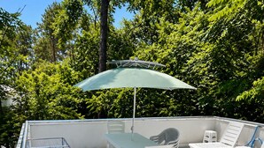 A deck with a table and chairs, a green umbrella, and a white railing. - Lovely private house on the Shekvetili coast (Shekvetili)