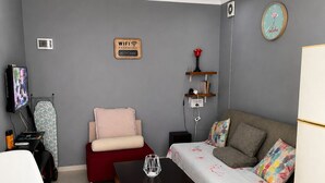 A living room with a sofa, armchair, coffee table, TV, and a clock on the wall. - Lovely private house on the Shekvetili coast (Shekvetili)