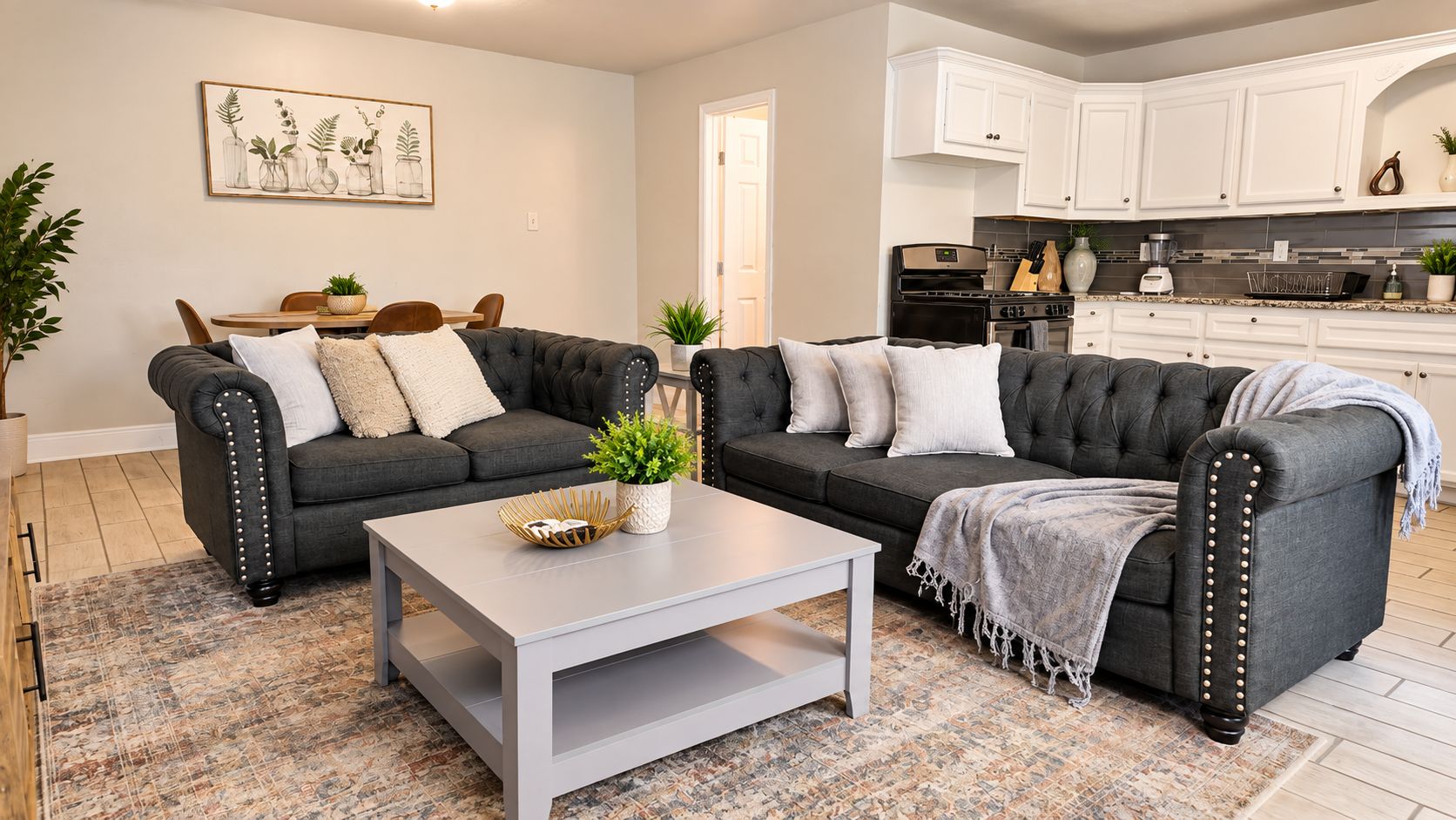 A modern living room with two dark grey sofas, a white coffee table, and a patterned rug.