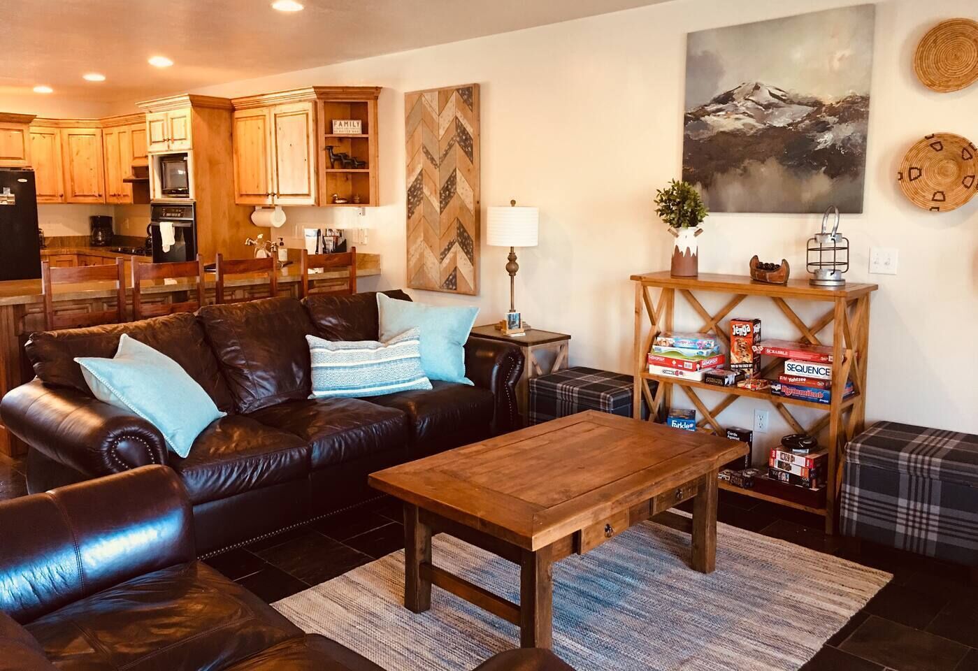 A cozy living room with a leather sofa, a wooden coffee table, and a kitchen in the background.
