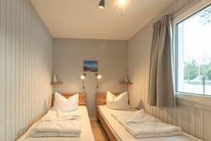 A room with two beds, a window with curtains, a picture on the wall, and two wall-mounted lights. - Modern Eingerichteter Doppelbungalow mit Garten in Mirow (Mirow)