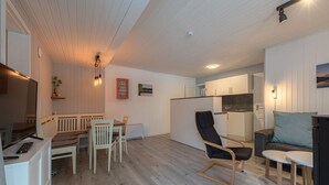 A modern living room with a dining area, a kitchen, and a seating area with a sofa and a chair. - Modern Eingerichteter Doppelbungalow mit Garten in Mirow (Mirow)