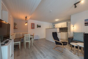A modern living room with a dining area, a kitchen, and a seating area with a sofa and a chair. - Modern Eingerichteter Doppelbungalow mit Garten in Mirow (Mirow)