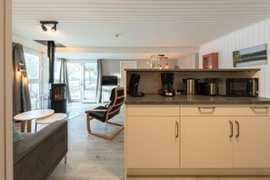A modern kitchen with a built-in stove, a coffee maker, and a microwave. - Modern Eingerichteter Doppelbungalow mit Garten in Mirow (Mirow)