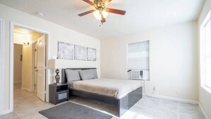 A bedroom with a bed, nightstands, a desk, a ceiling fan, and a window with blinds. - Pet-Friendly Houston Apartment w\ Backyard (Houston)