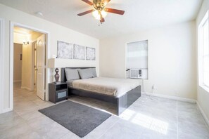 A bedroom with a bed, nightstands, a desk, a ceiling fan, and a window with blinds. - Pet-Friendly Houston Apartment w\ Backyard (Houston)