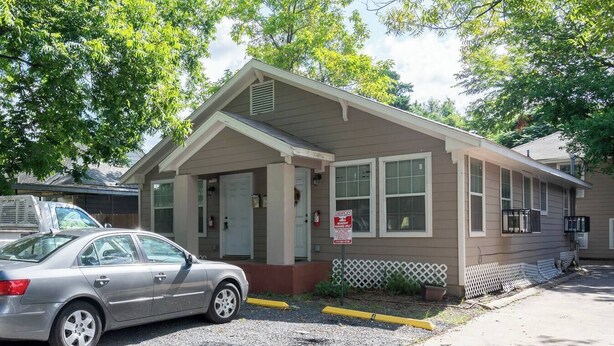 A single-story building with a front porch, a garage, and a driveway. - Pet-Friendly Houston Apartment w\ Backyard (Houston)