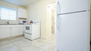 A kitchen with white cabinets, a stove, a microwave, and a refrigerator. - Pet-Friendly Houston Apartment w\ Backyard (Houston)