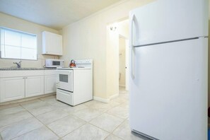 A kitchen with white cabinets, a stove, a microwave, and a refrigerator. - Pet-Friendly Houston Apartment w\ Backyard (Houston)