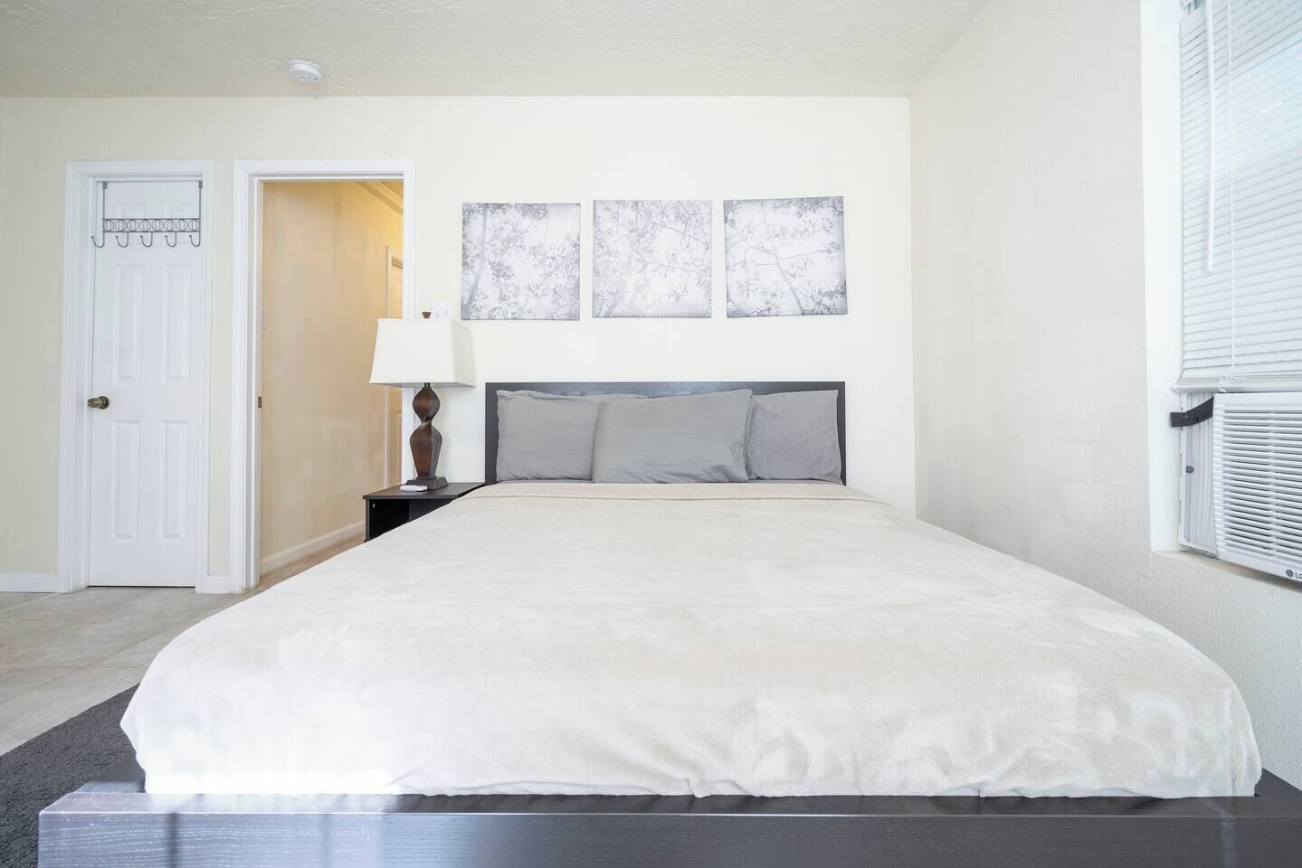 A bedroom with a bed, a nightstand, a lamp, and three wall-mounted pictures.