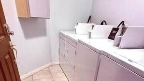 A laundry room with a washing machine, dryer, and cabinets. - Pet-Friendly Houston Apartment w\ Backyard (Houston)