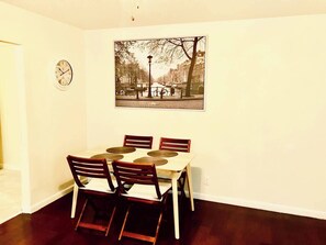 A dining area with a table and chairs, a wall clock, and a framed picture. - Pet-Friendly Houston Apartment w\ Backyard (Houston)
