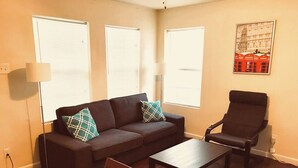 A living room with a sofa, armchair, coffee table, and a lamp. - Pet-Friendly Houston Apartment w\ Backyard (Houston)