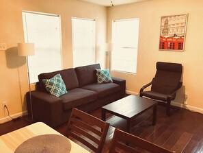 A living room with a sofa, armchair, coffee table, and a lamp. - Pet-Friendly Houston Apartment w\ Backyard (Houston)