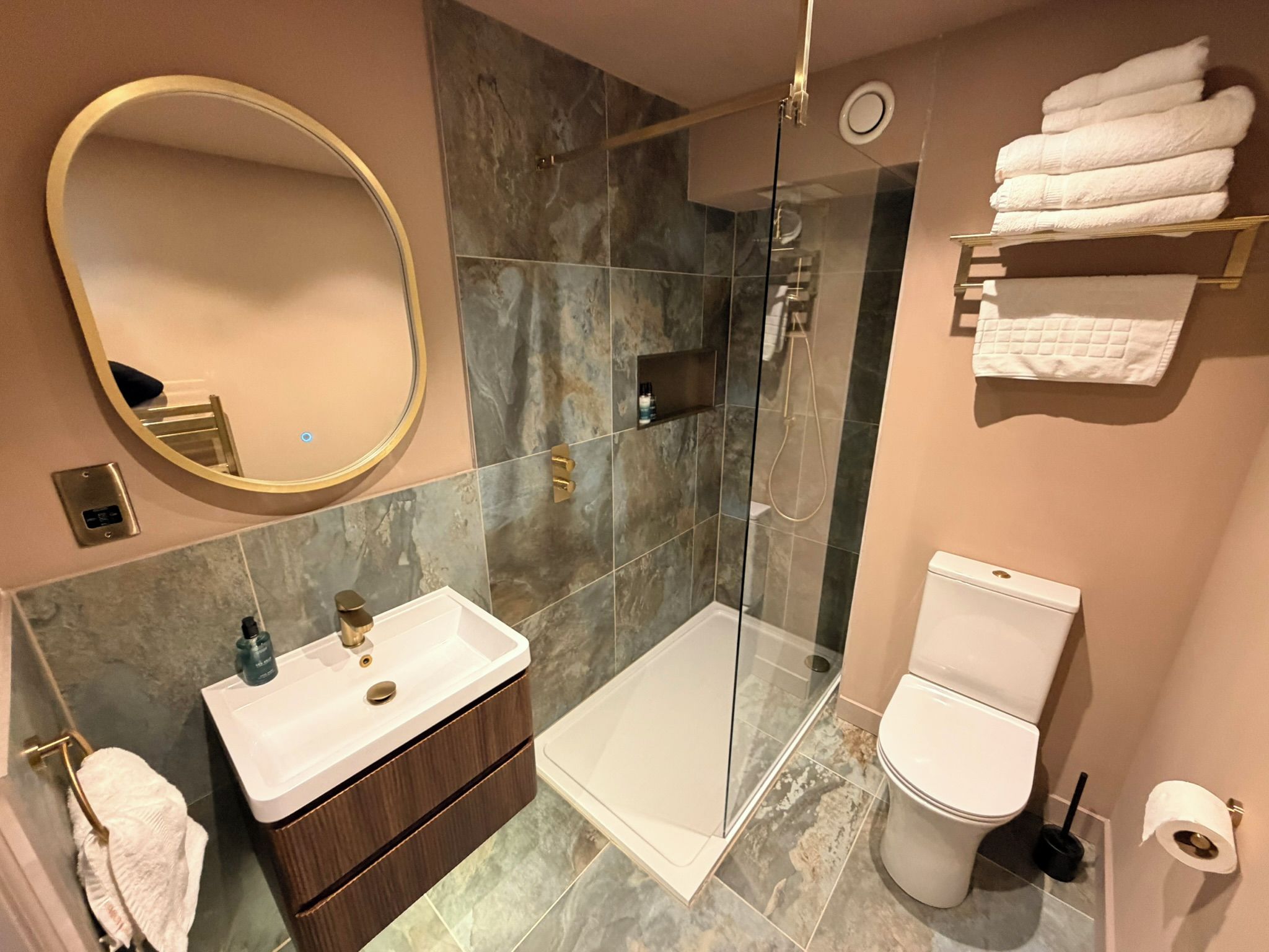 A modern bathroom with a glass-enclosed shower, a vanity with a sink, a toilet, and a mirror.