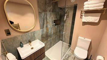A modern bathroom with a glass-enclosed shower, a vanity with a sink, a toilet, and a mirror.