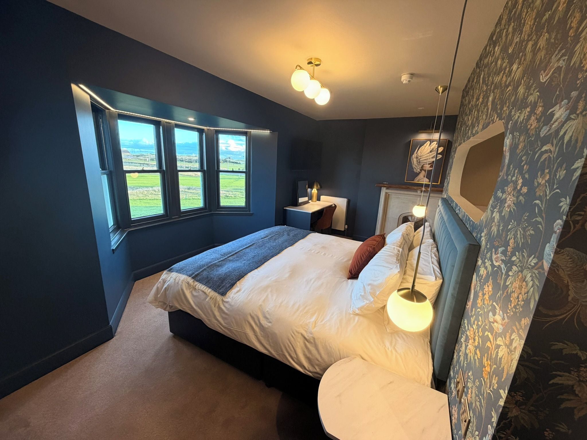Een slaapkamer met een groot bed, een bureau en uitzicht op de omgeving door een raam.