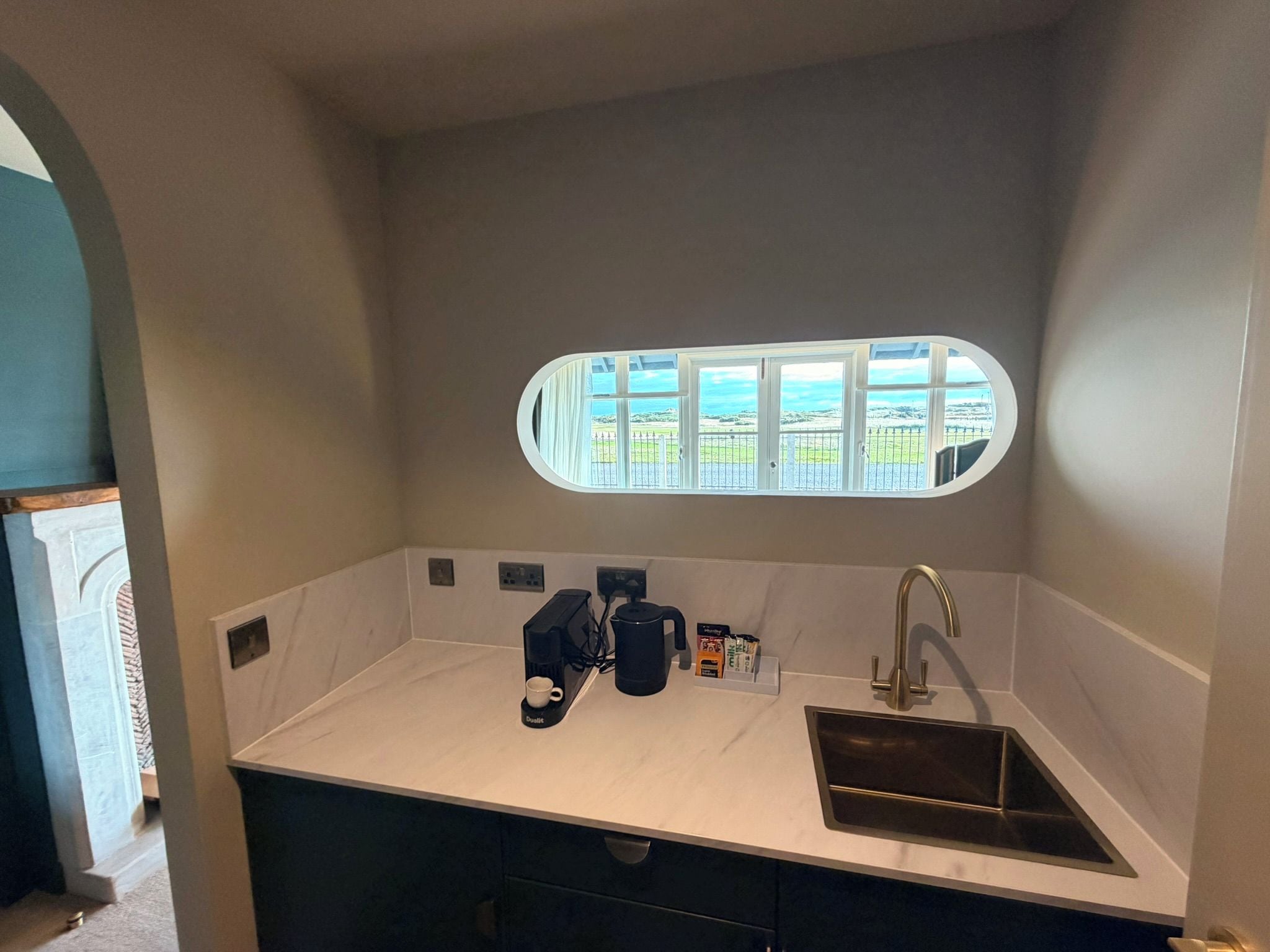 Una cocina compacta con un lavamanos empotrado, una cafetera y vistas a través de una ventana.