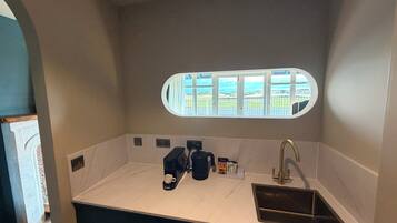 Una cocina compacta con un lavamanos empotrado, una cafetera y vistas a través de una ventana.