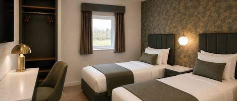 A hotel room with two beds, a desk, a chair, and a wardrobe.