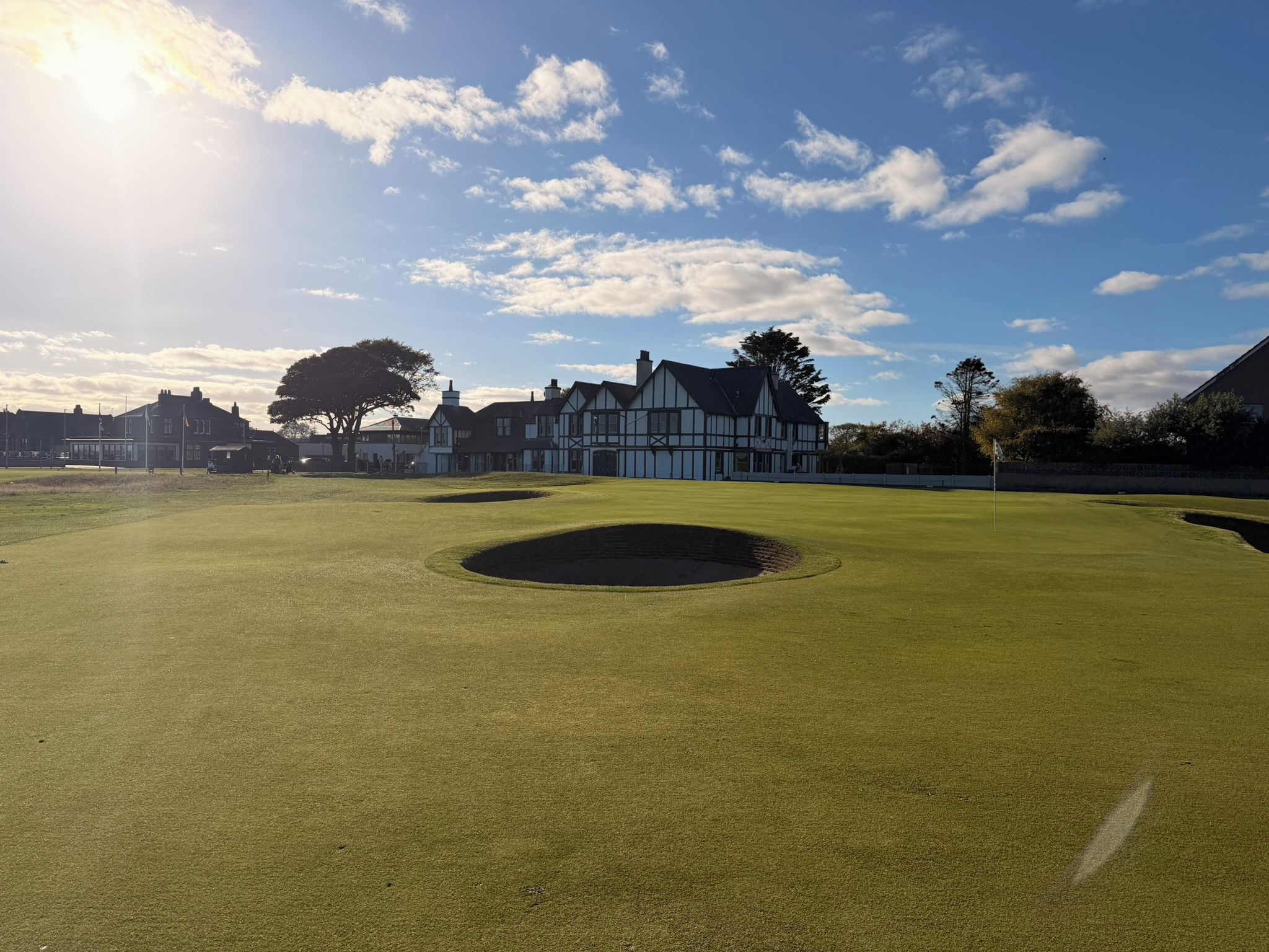 A golf course with a clubhouse and a large tree in the foreground.