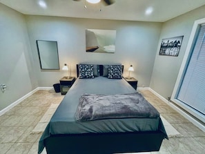 A bedroom with a bed, nightstands, a mirror, and artwork on the walls. - Bellaire Home Stay w/Pool & Workspace (Houston)