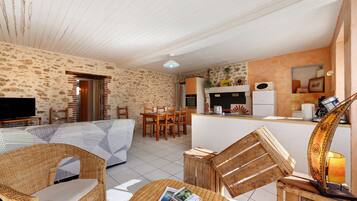 Un salon confortable avec un canapé, des fauteuils, un téléviseur et un coin repas comprenant une table et des chaises.
