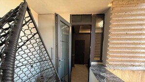 Una habitación con una silla colgante, un vidrio corredizo que da a un pasillo y piso de madera.