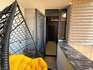 A room with a hanging chair, a glass door leading to a hallway, and a wooden floor. - Panoramic Ararat View Apartment (Yerevan)