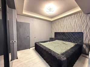 A bedroom with a large bed, a dark headboard, and a patterned wall. - Panoramic Ararat View Apartment (Yerevan)