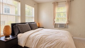 A bedroom with a bed, nightstands, a lamp, and a window with curtains. - Pet-Friendly Home w/ Patio & Backyard (Houston)