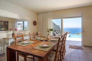 A dining area with a view of the sea, a ship's wheel decoration, and a buffet counter. - Miranda Infinity Pool Villa Pefkos Rhodes (Rhodes)
