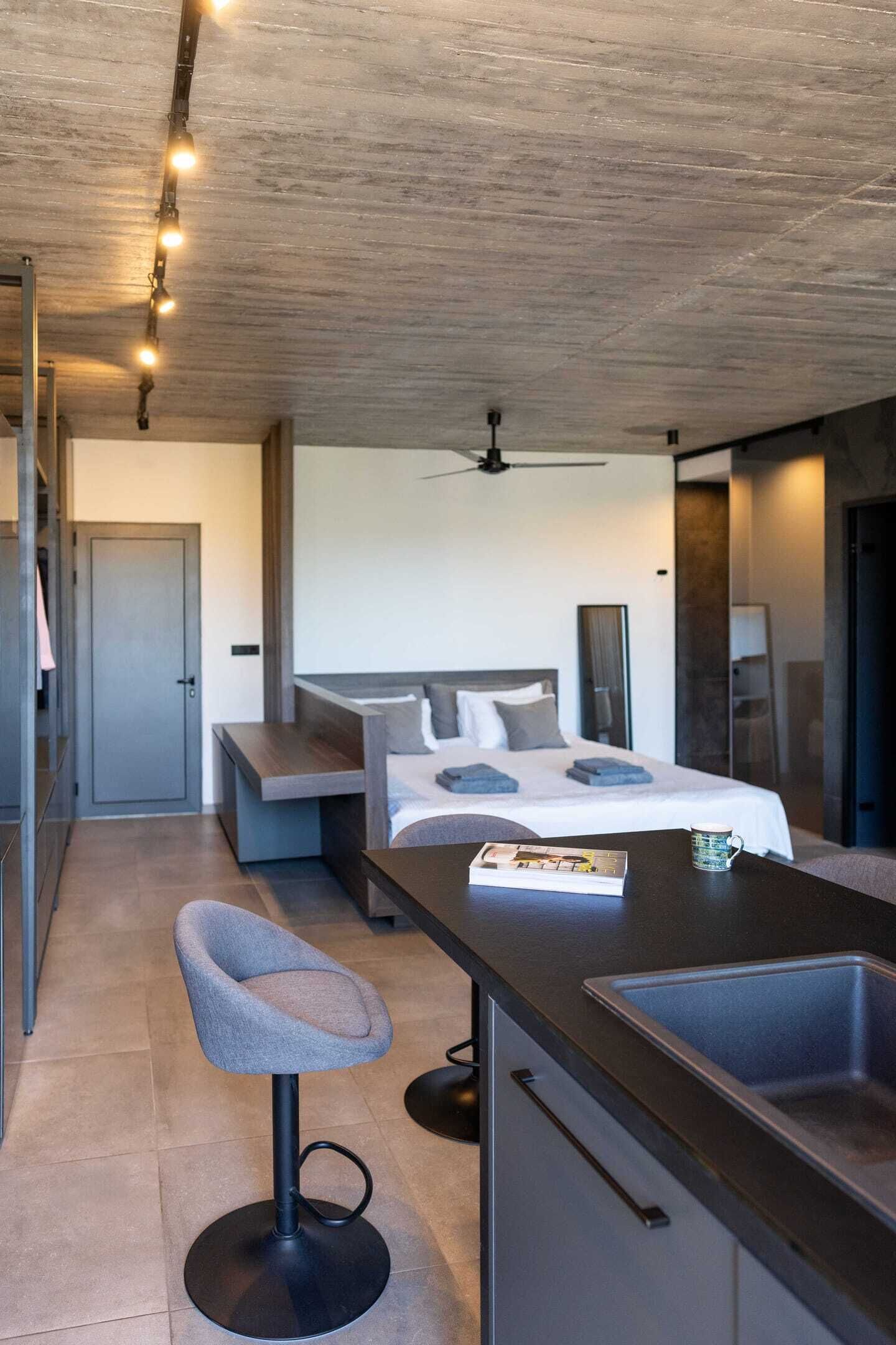 A modern hotel room with a bed, a desk, a chair, and a large window.