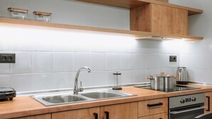 Una cocina moderna con armarios de madera, un lavamanos de acero inoxidable y un horno empotrado.