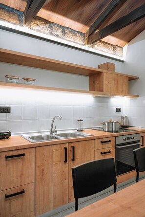 A modern kitchen with wooden cabinets, a stainless steel sink, and a built-in oven. - Manolis Seaside Villa with Private Pool, 500m from the Beach (Rhodes)