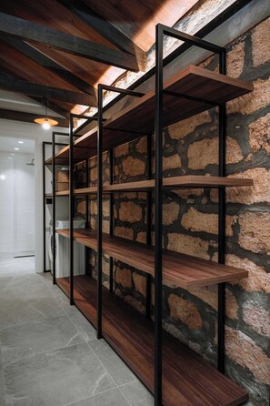 A hallway with a stone wall and wooden shelves. - Manolis Seaside Villa with Private Pool, 500m from the Beach (Rhodes)