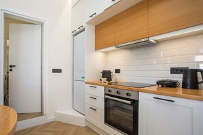 A compact kitchen with white cabinetry, a wooden countertop, a built-in oven, and a coffee maker. - 2BR Apartment with 2 Bathrooms in Rhodes Center (Rhodes)