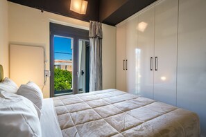 A bedroom with a bed, a wardrobe, and a view of the outdoors. - Crethion | Private Pool, Jacuzzi, Gym & Games Room (Violi Charaki)