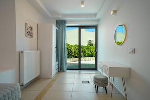 A modern room with a radiator, a sliding glass door leading to a balcony, a small round mirror, and a white cabinet. - Crethion | Private Pool, Jacuzzi, Gym & Games Room (Violi Charaki)