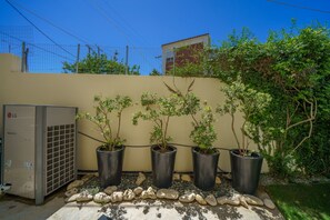 A row of potted plants with a utility box and a fence in the background. - Crethion | Private Pool, Jacuzzi, Gym & Games Room (Violi Charaki)